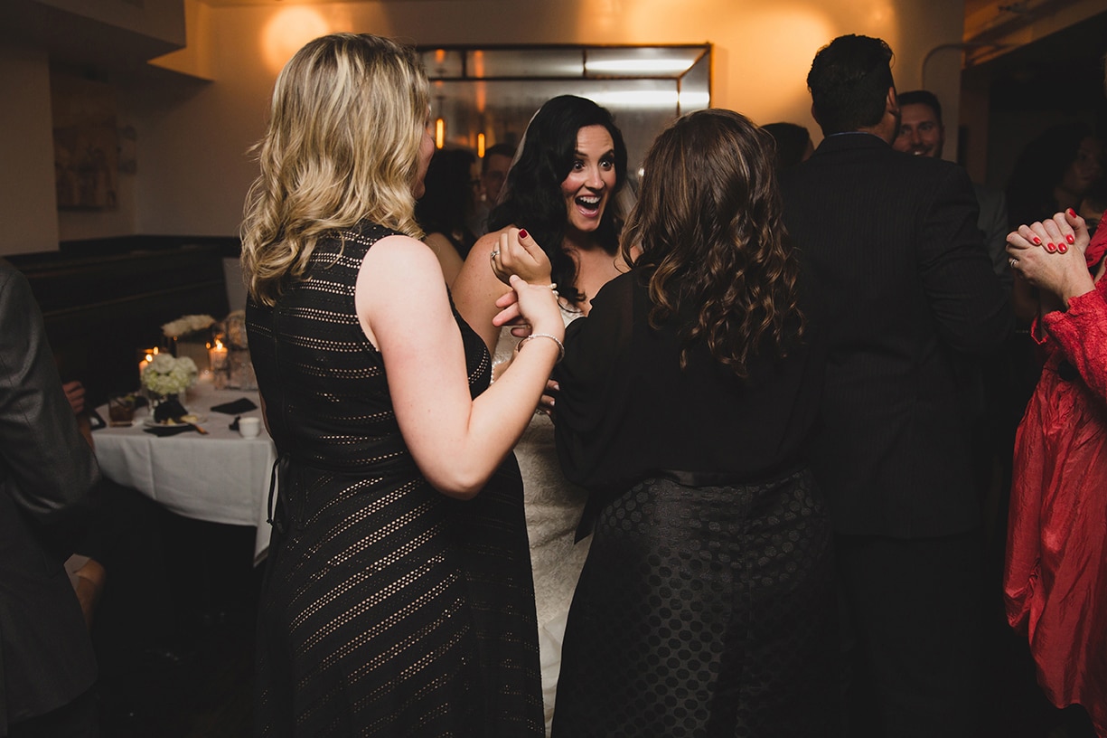 A documentary photograph of a bride talking and laughing with friends during her marliave wedding reception in Boston, Massachusetts