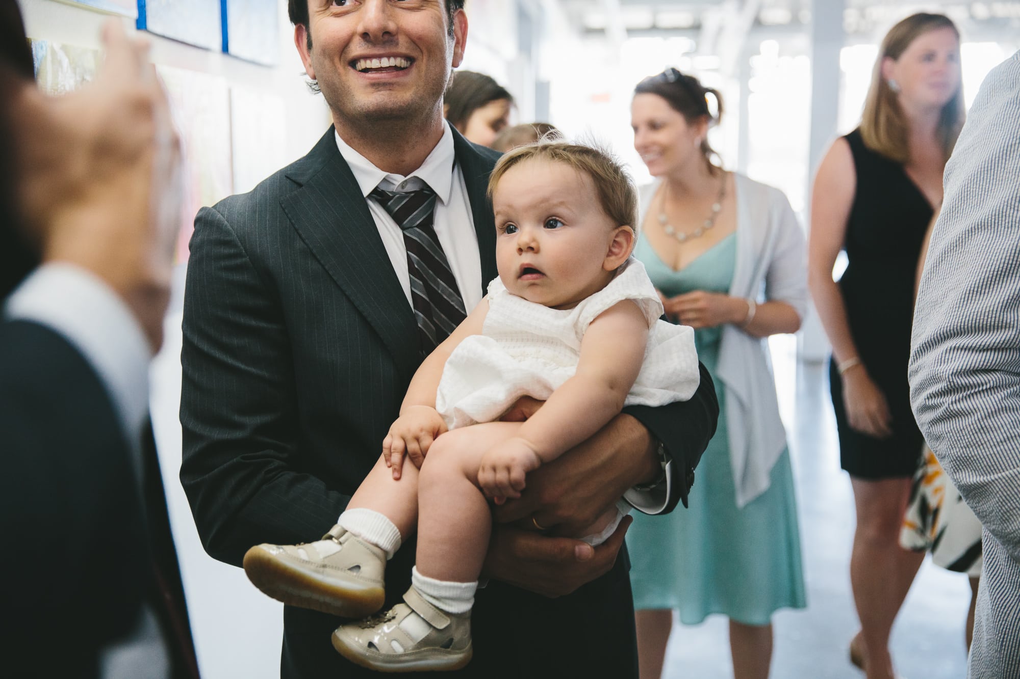 A documentary photograph of a baby watching a guest talk during an Artists for Humanity Wedding in Boston