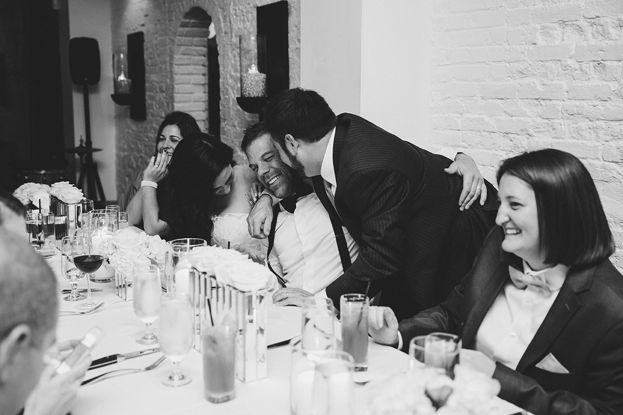 A documentary photograph of guests talking and laughing during a marliave wedding reception in Boston, Massachusetts