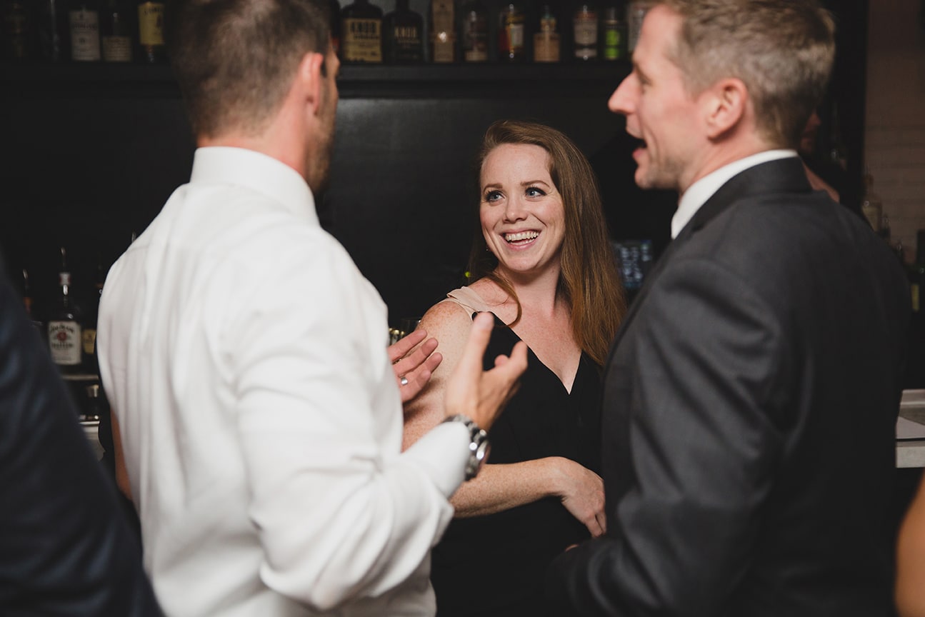 A documentary photograph of guests laughing during a marliave wedding reception in Boston, Massachusetts