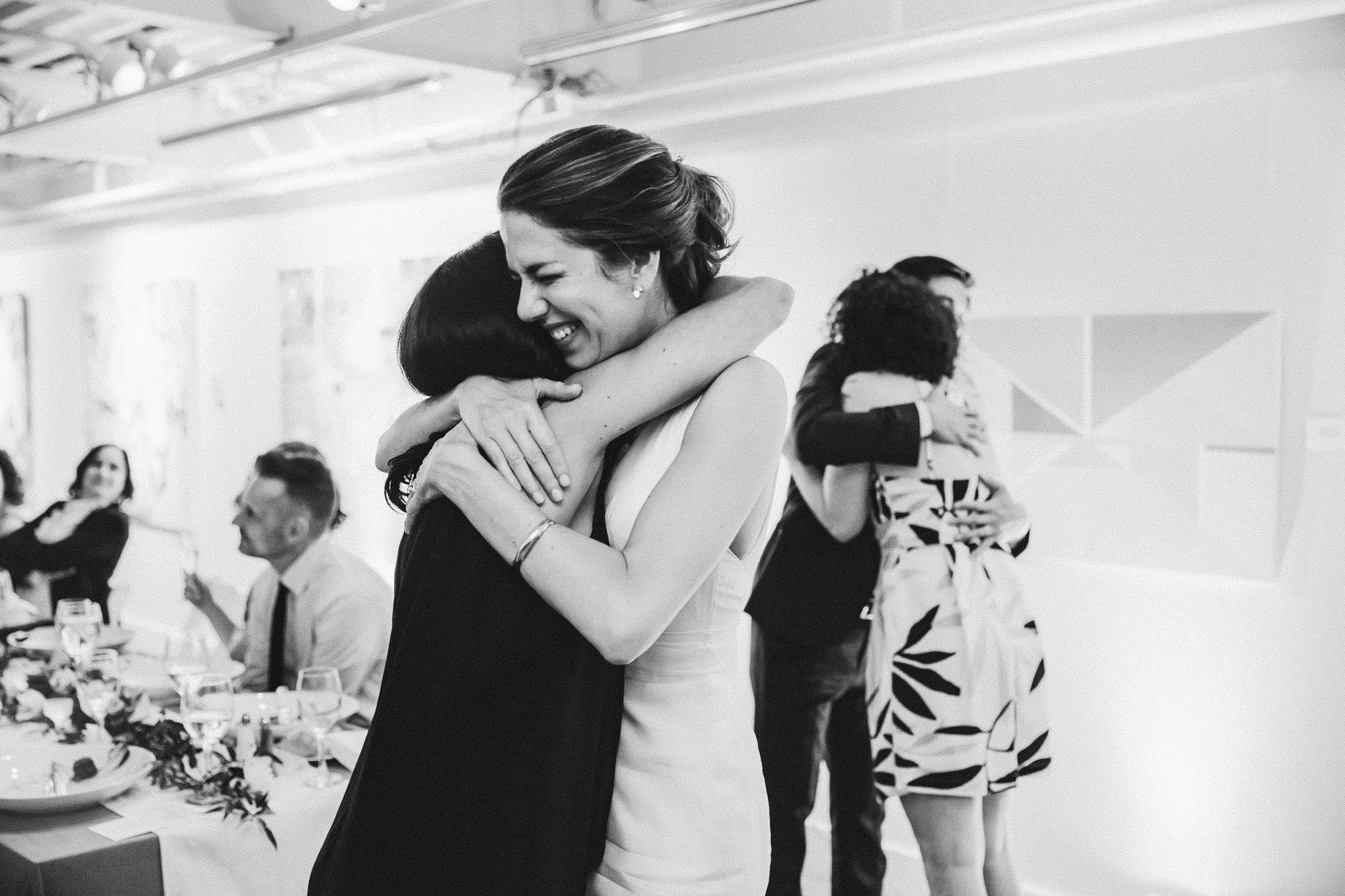 A documentary photograph of a bride and groom hugging their friends during an Artists for Humanity Wedding in Boston