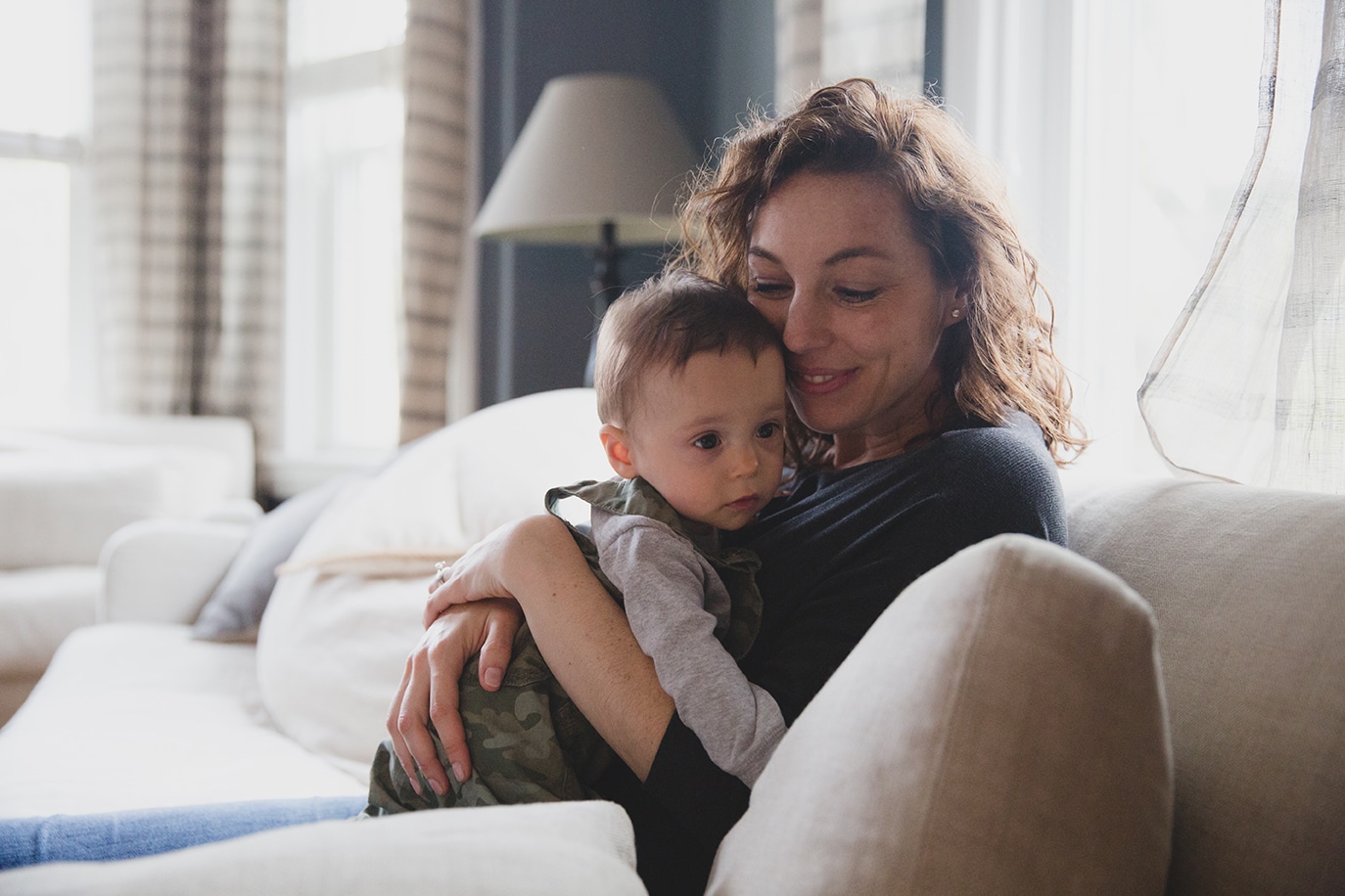 A documentary photograph of a mom hugging her baby boy during an in home family session in Jamaica Plain