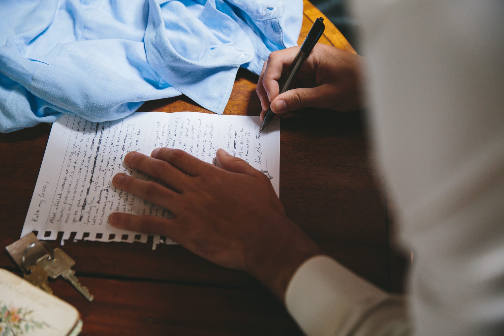A documentary photograph of a groom writing a letter to his bride before their State Room Wedding in Boston, Massachusetts