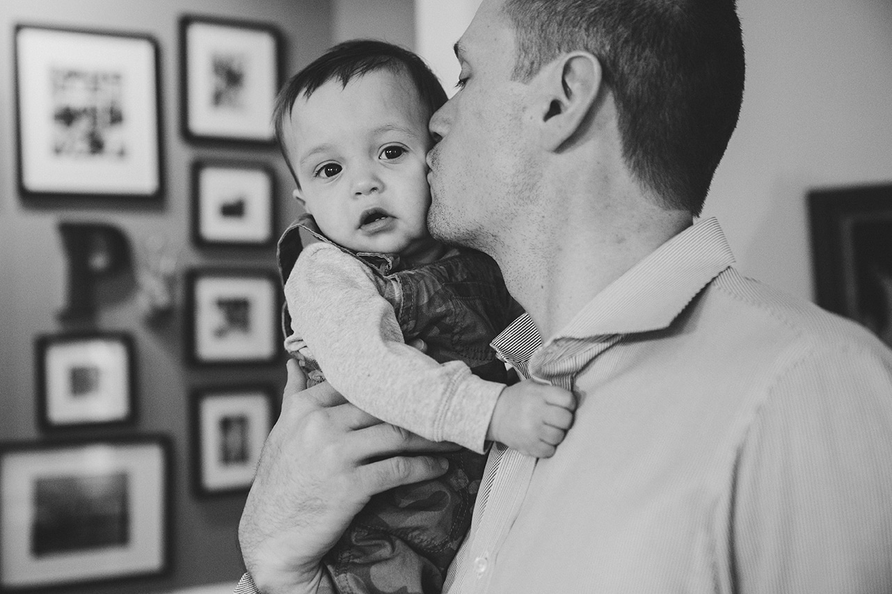 A documentary photograph of a dad kissing his son during an in home family session in Boston, Massachusetts