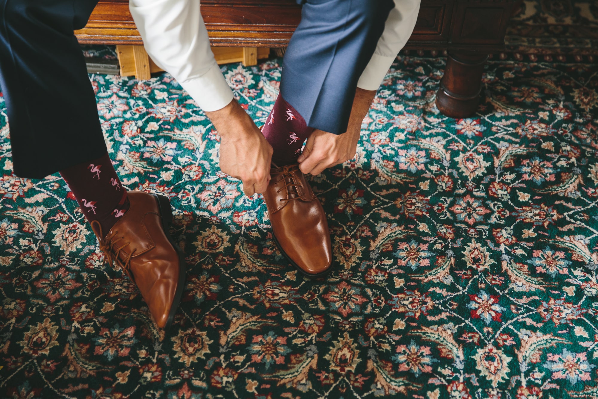 A documentary photograph of a groomsmen tying his shoes before a State Room Wedding in Boston, Massachusetts
