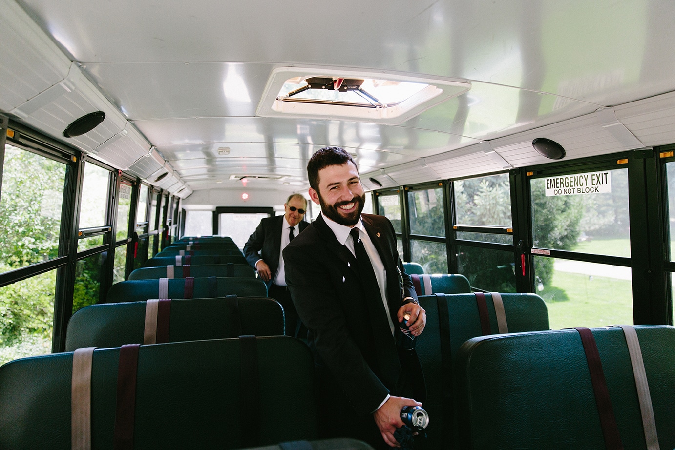 A documentary photograph of a groom arriving to his Moraine Farm wedding in Beverly, Massachusetts on a school bus