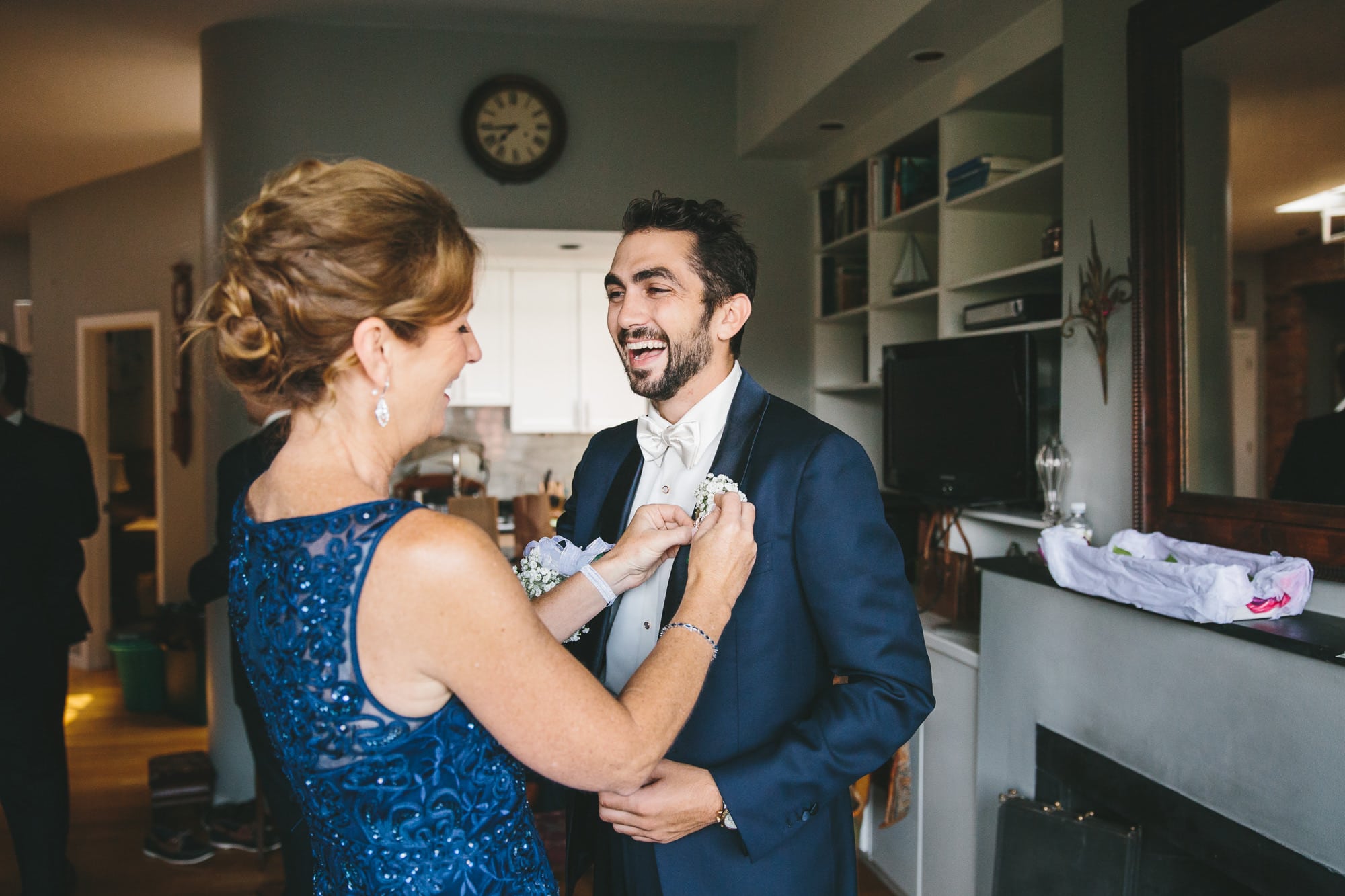 A documentary photograph of a mother putting a boutonnière on her son before his State Room Wedding in Boston, Massachusetts