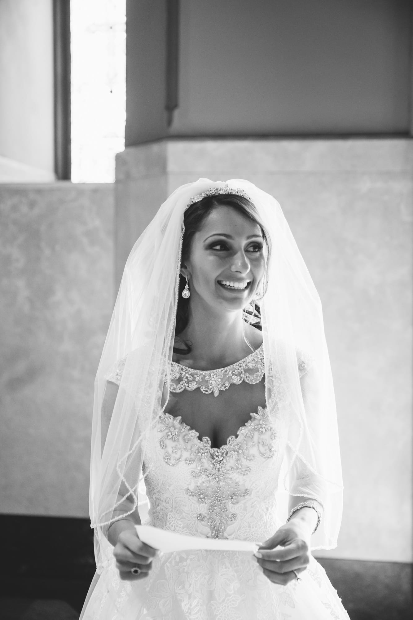 A documentary portrait of a bride smiling moments before she walks down the aisle of the Cathedral of the Holy Cross during her State Room Wedding in Boston, Massachusetts