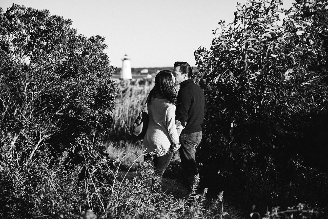 A documentary photograph of a couple kissing near the lighthouse during their honeymoon photo session on Martha's Vineyard
