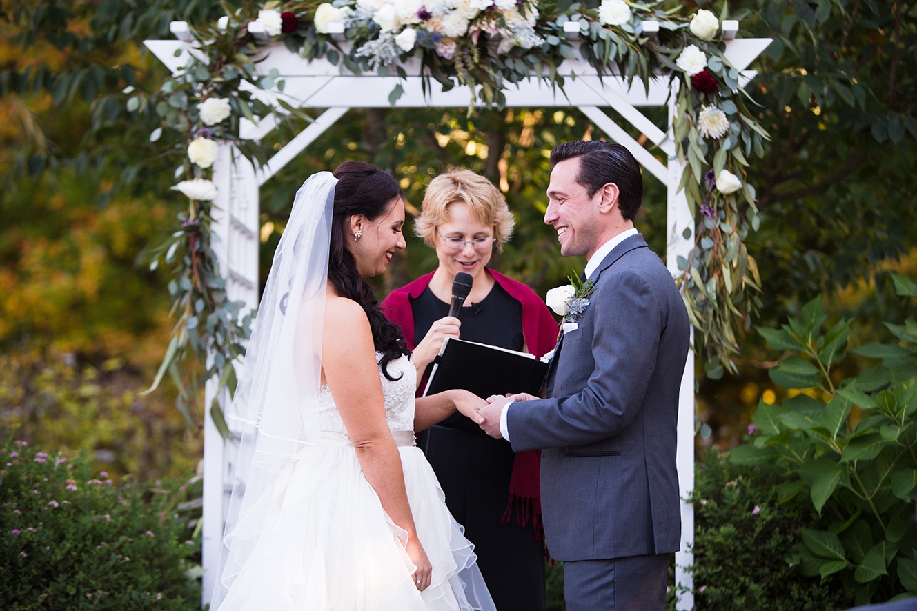 A documentary photograph of a bride and groom exchanging rings during their outdoor ceremony at Harrington Farm in Princeton, Massachusetts
