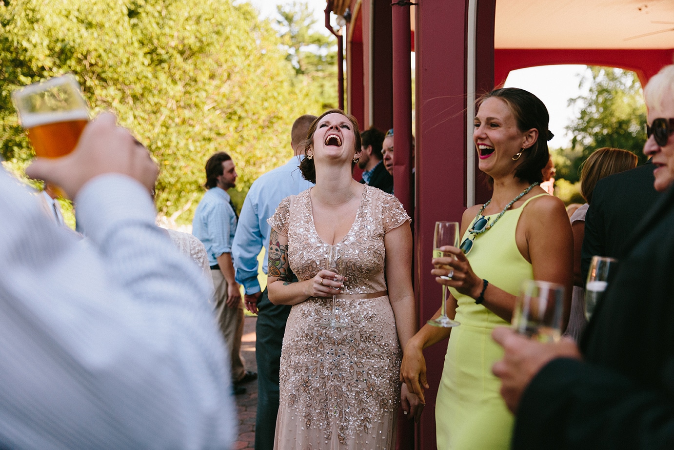 A documentary photograph of guests laughing during a Moraine Farm Wedding in Beverly, Massachusetts