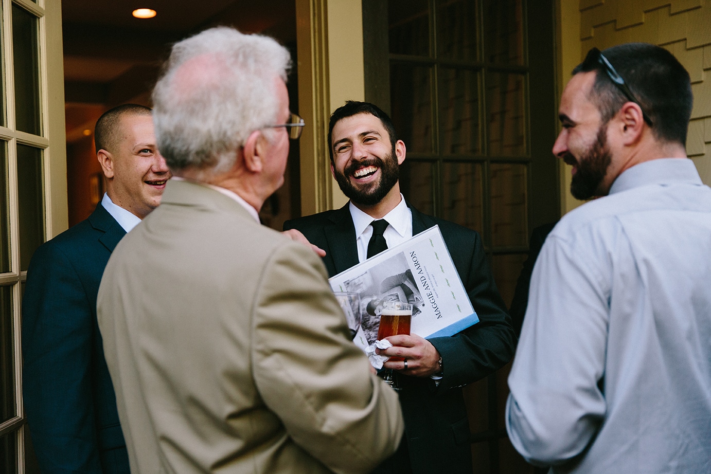 A documentary photograph of a groom celebrating with guests during his Moraine Farm Wedding in Beverly, Massachusetts