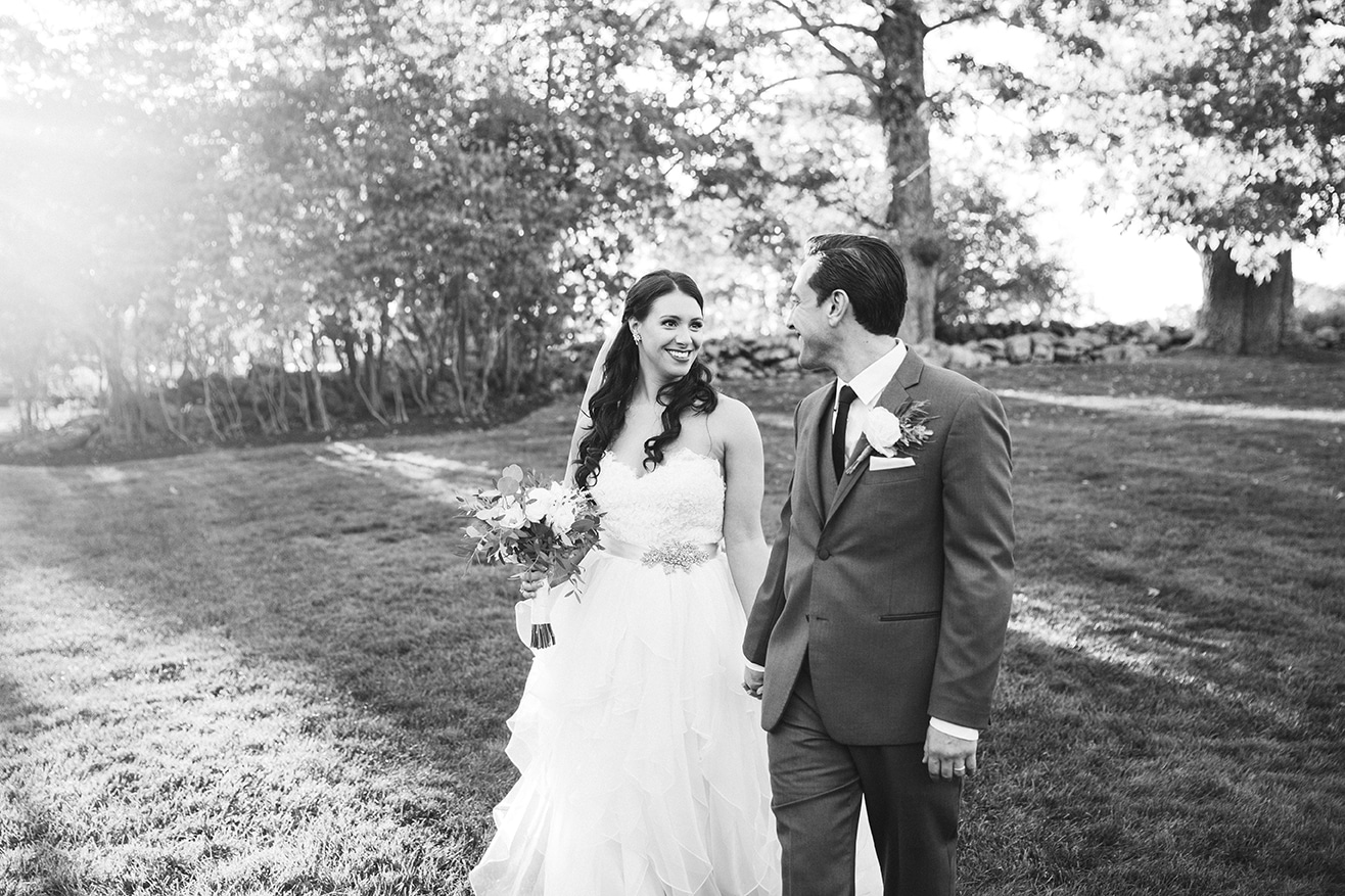 A documentary photograph of a bride and groom walking together during their Harrington Farm Wedding in Princeton, Massachusetts