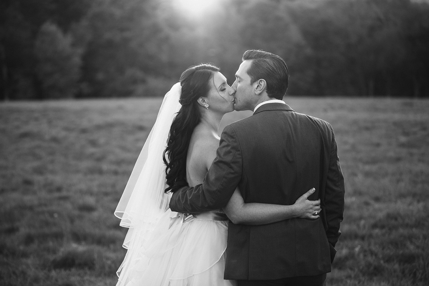 A documentary photograph of a bride and groom kissing at sunset during their Harrington Farm Wedding in Princeton, Massachusetts