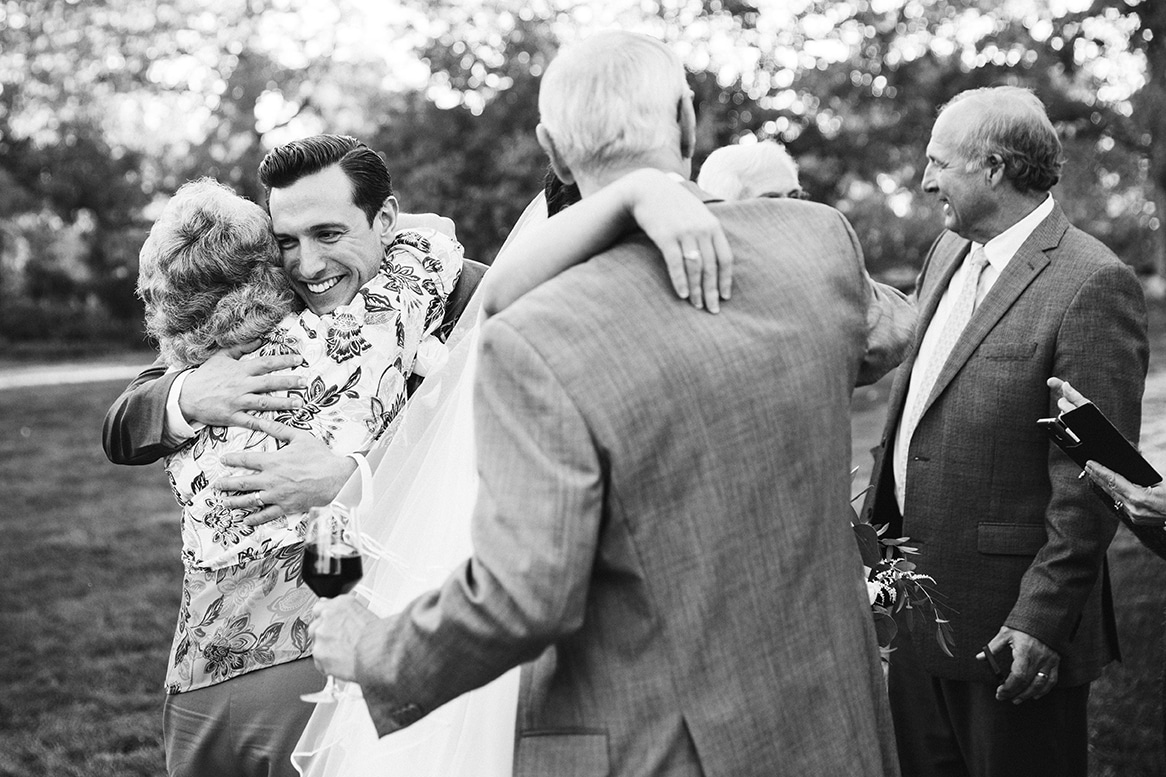 A documentary photograph of a bride and groom hugging their guests during their Harrington Farm Wedding in Princeton, Massachusetts