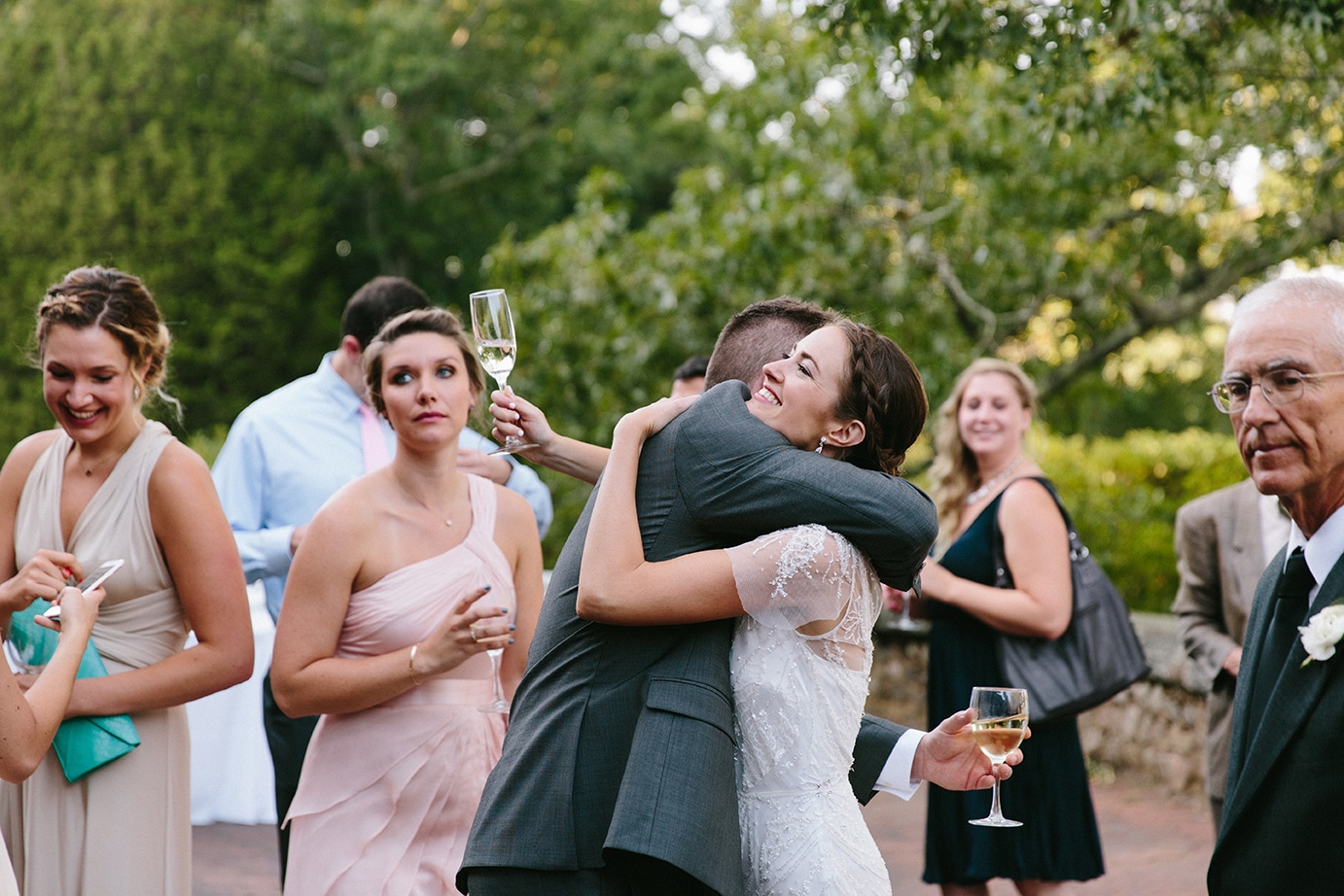A documentary photograph of a bride hugging her friend during her Moraine Farm Wedding in Beverly, Massachusetts