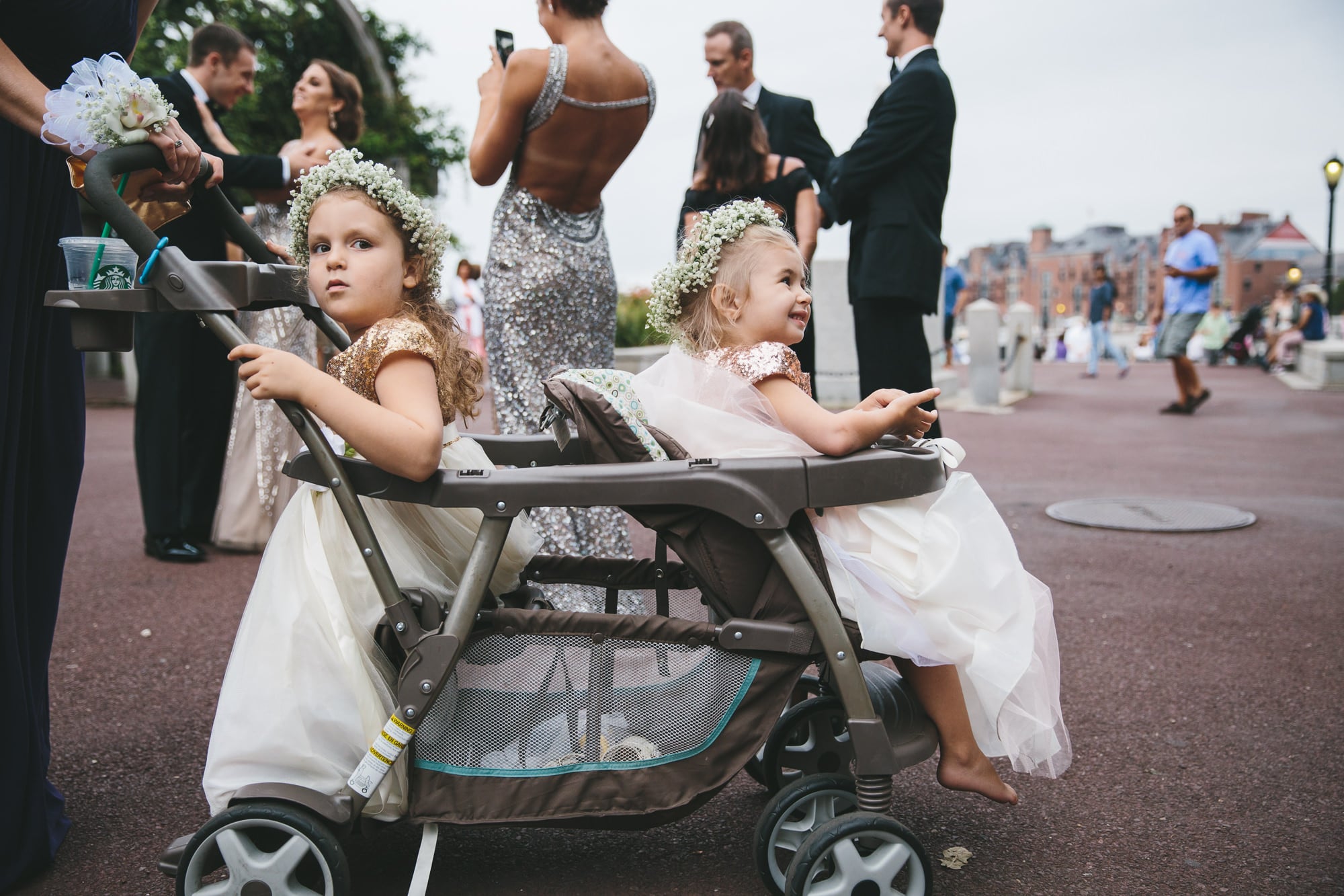 A documentary photograph of two flower girls sitting in a stroller at Christopher Columbus Park during a State Room Wedding in Boston, Massachusetts