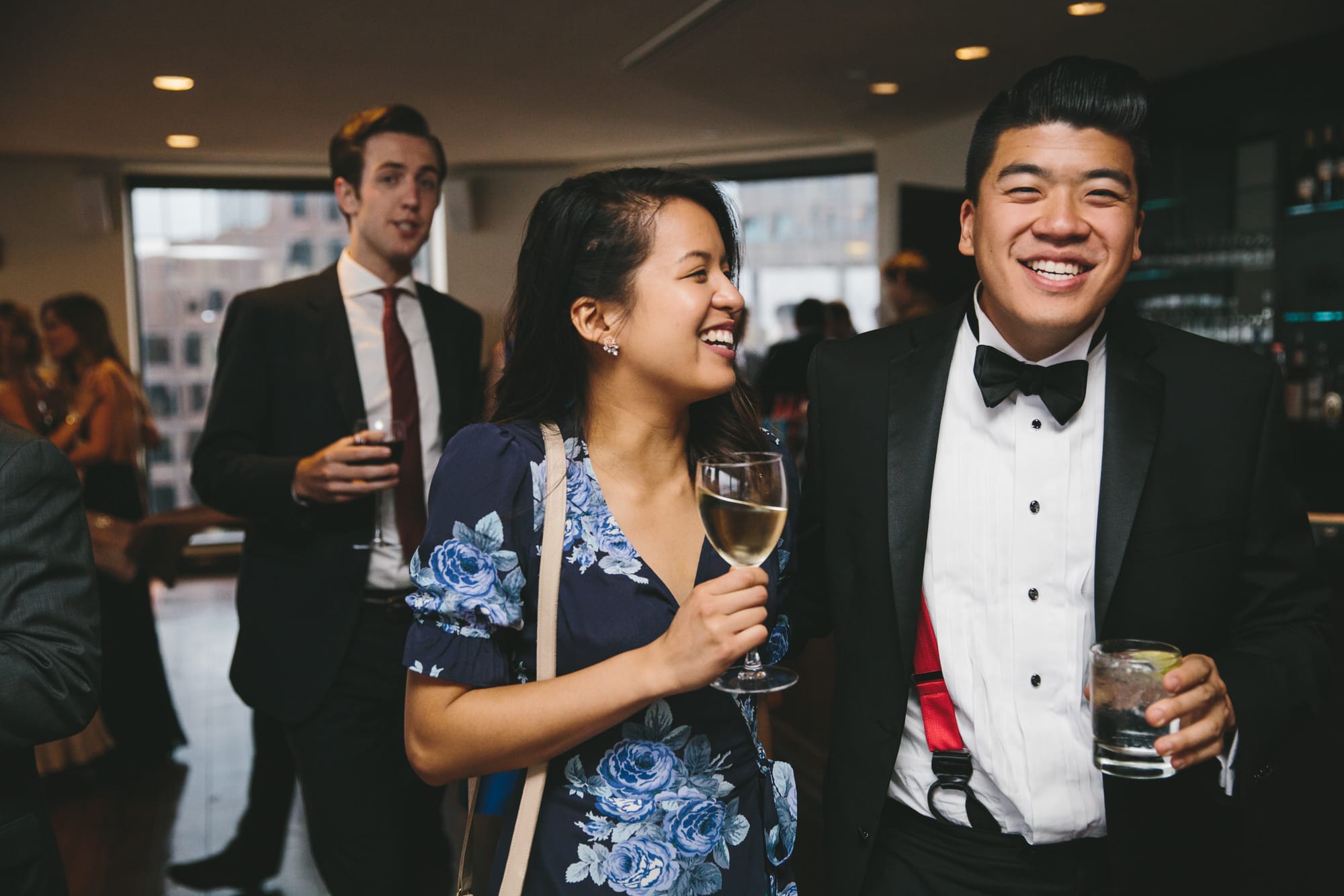 A documentary photograph of wedding guests talking and laughing during the cocktail hour of a State Room Wedding in Boston, Massachusetts