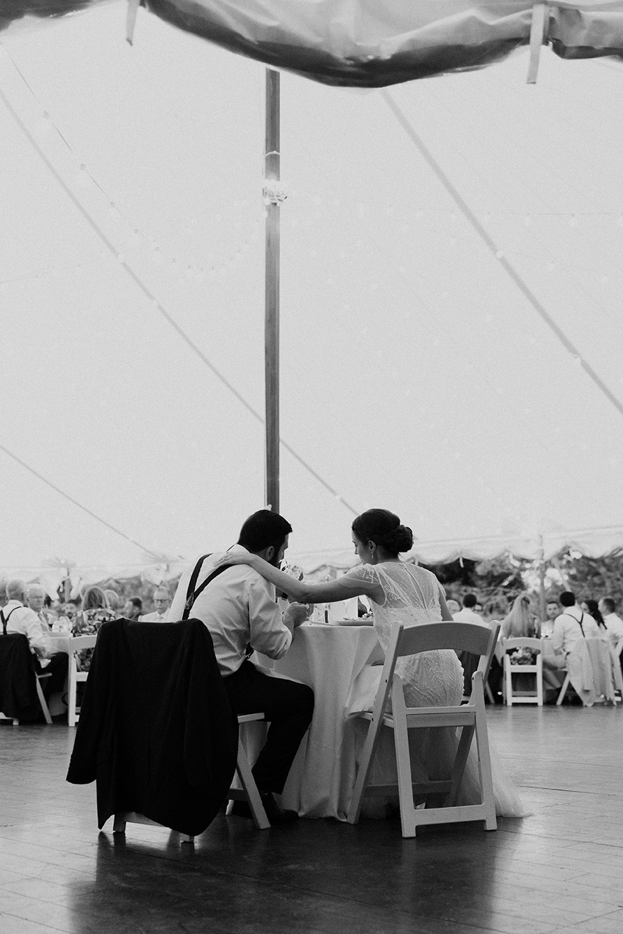 A documentary photograph of a bride and groom eating dinner together during their Moraine Farm Wedding in Beverly, Massachusetts