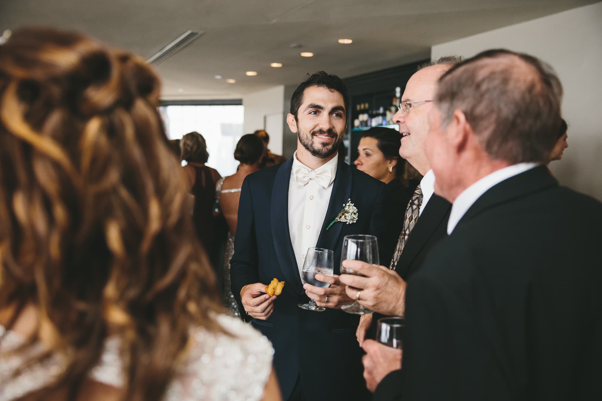 A documentary photograph of groom talking with guests during his State Room Wedding in Boston, Massachusetts