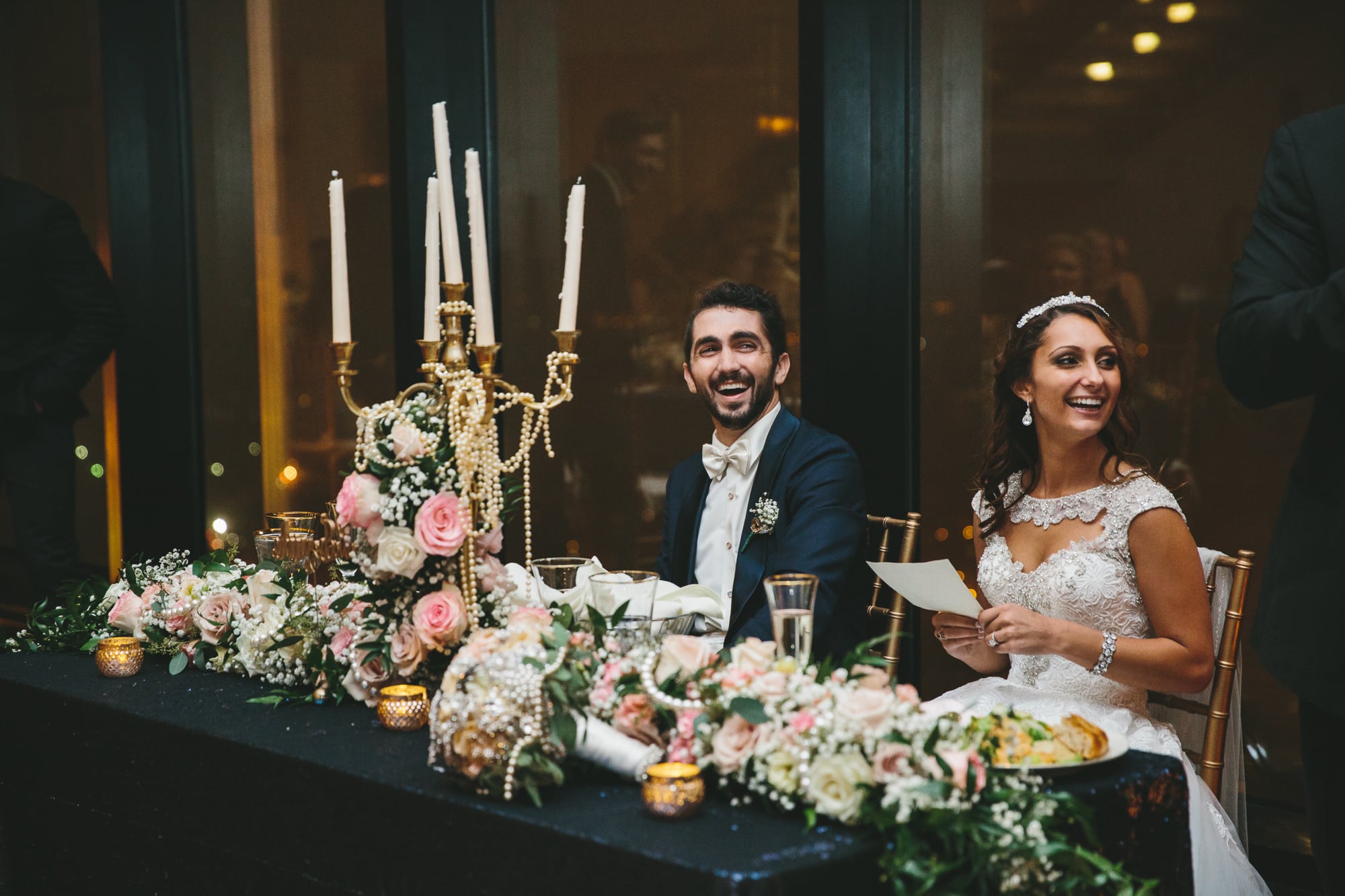 A documentary photograph of a bride and groom laughing during the toasts at their State Room Wedding