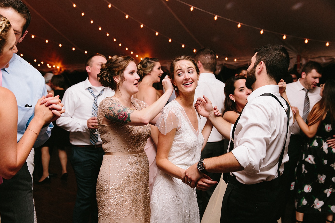 A documentary photograph of a bridesmaid fixing the brides hair while dancing during a Moraine Farm Wedding in Beverly, Massachusetts
