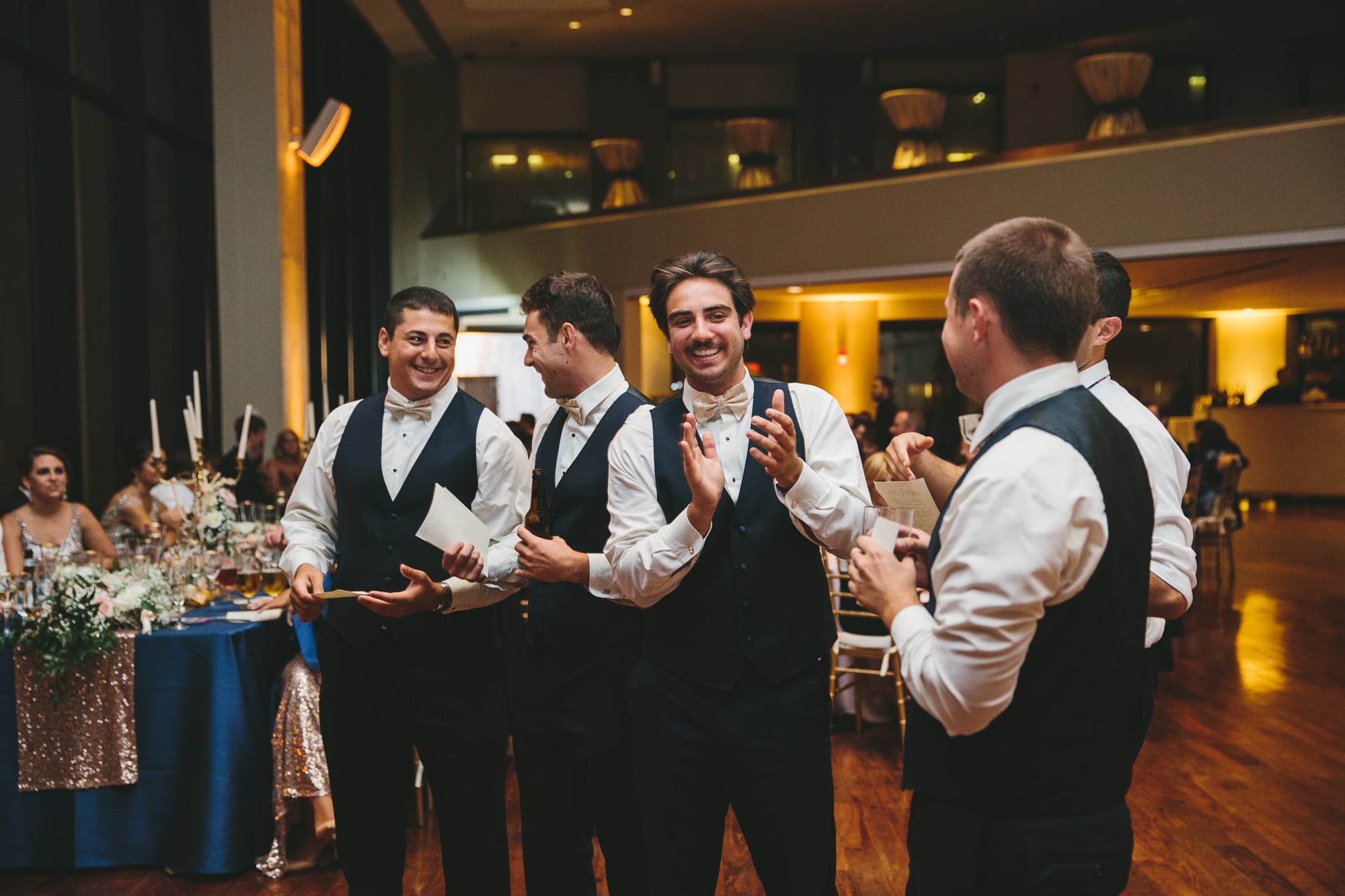 A documentary photograph of groomsmen clapping during their wedding speech at a State Room Wedding in Boston, Massachusetts