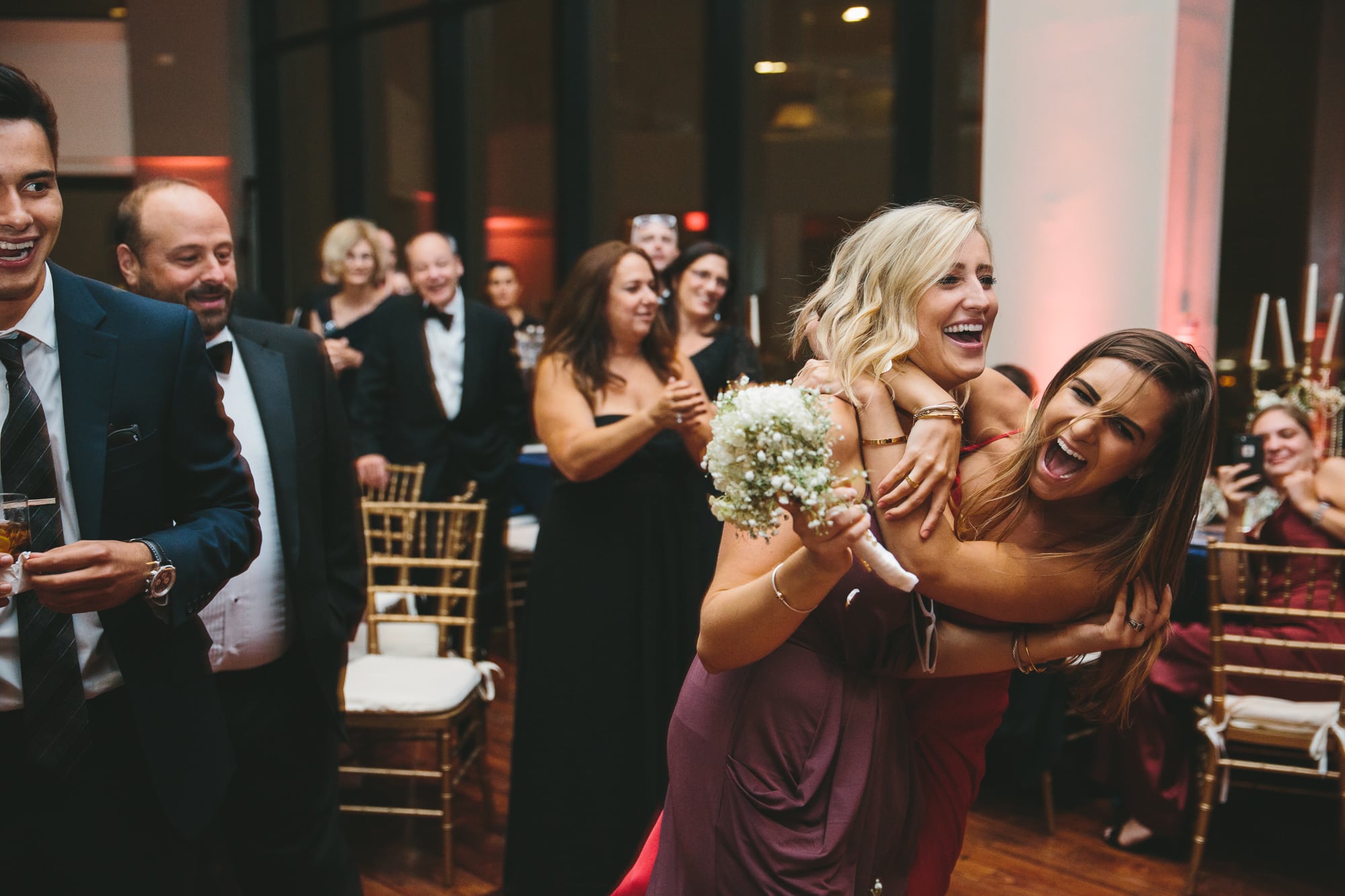 A documentary photograph of guests fighting over the bouquet toss during a State Room Wedding in Boston, Massachusetts