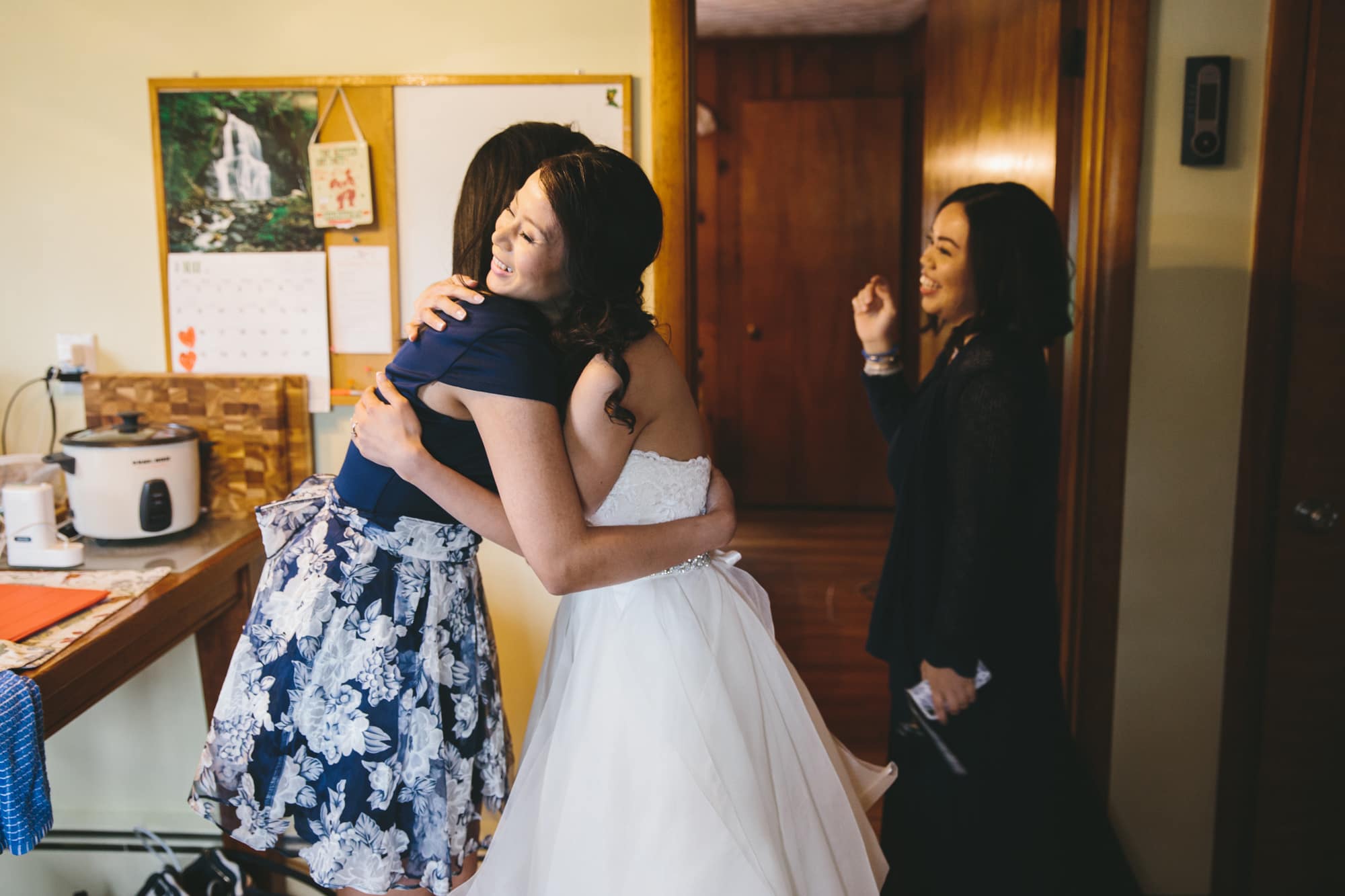 A documentary photograph of a bride hugging her friend while they get ready for a tower hill wedding in Boylston, Massachusetts