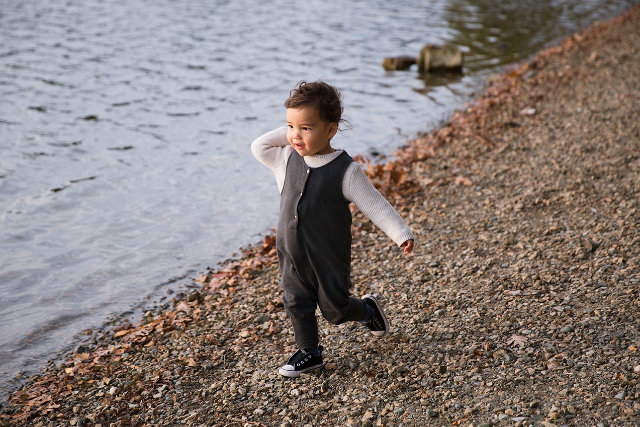 A documentary photograph of a toddler throwing bread for ducks during a Jamaica Pond family photo session in Boston