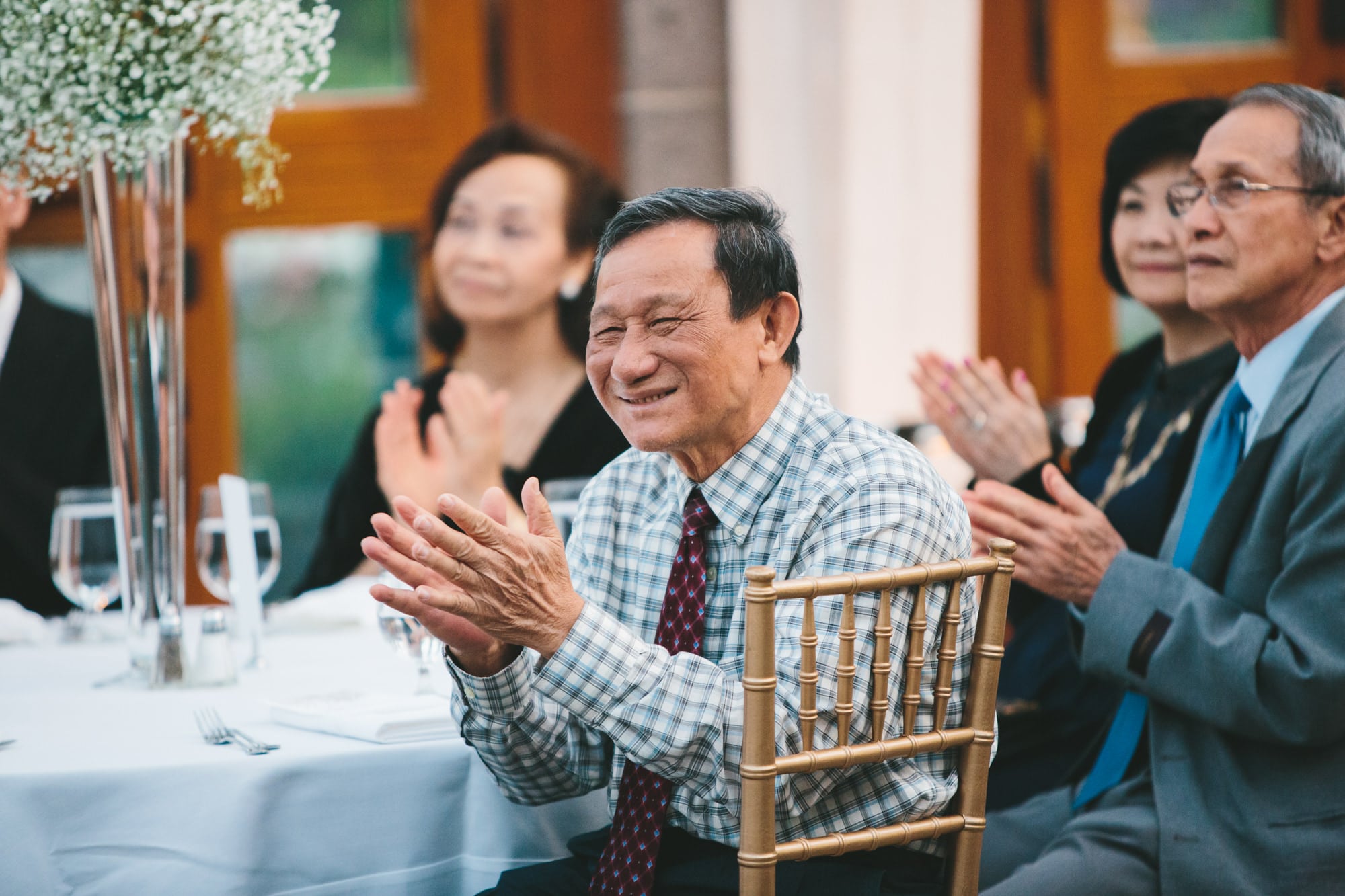 A documentary photograph of a father clapping and smiling during a Tower Hill Wedding Reception in Boylston, Massachusetts