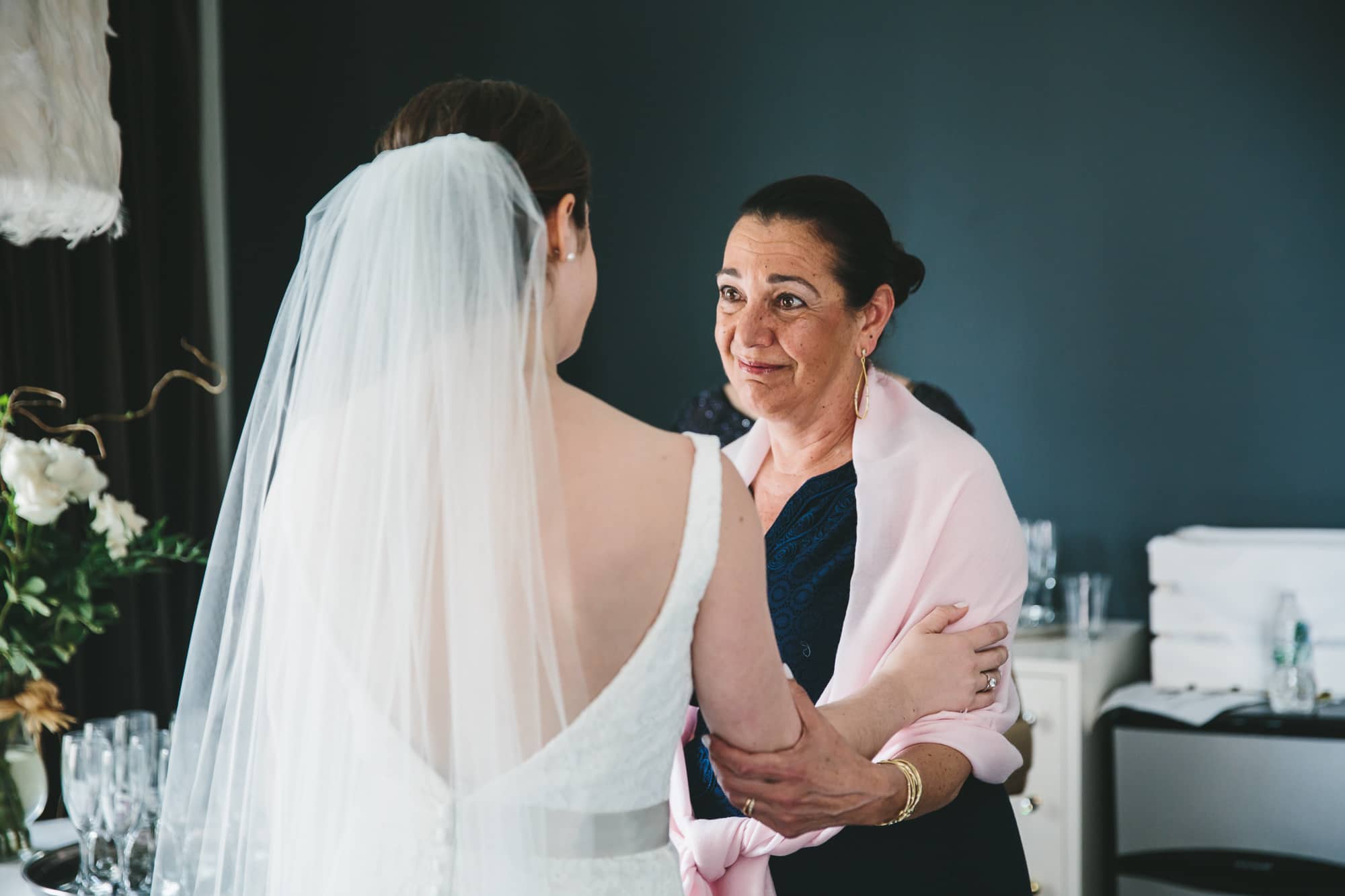 A documentary photograph of a bride hugging her mother in law before her State Room Wedding