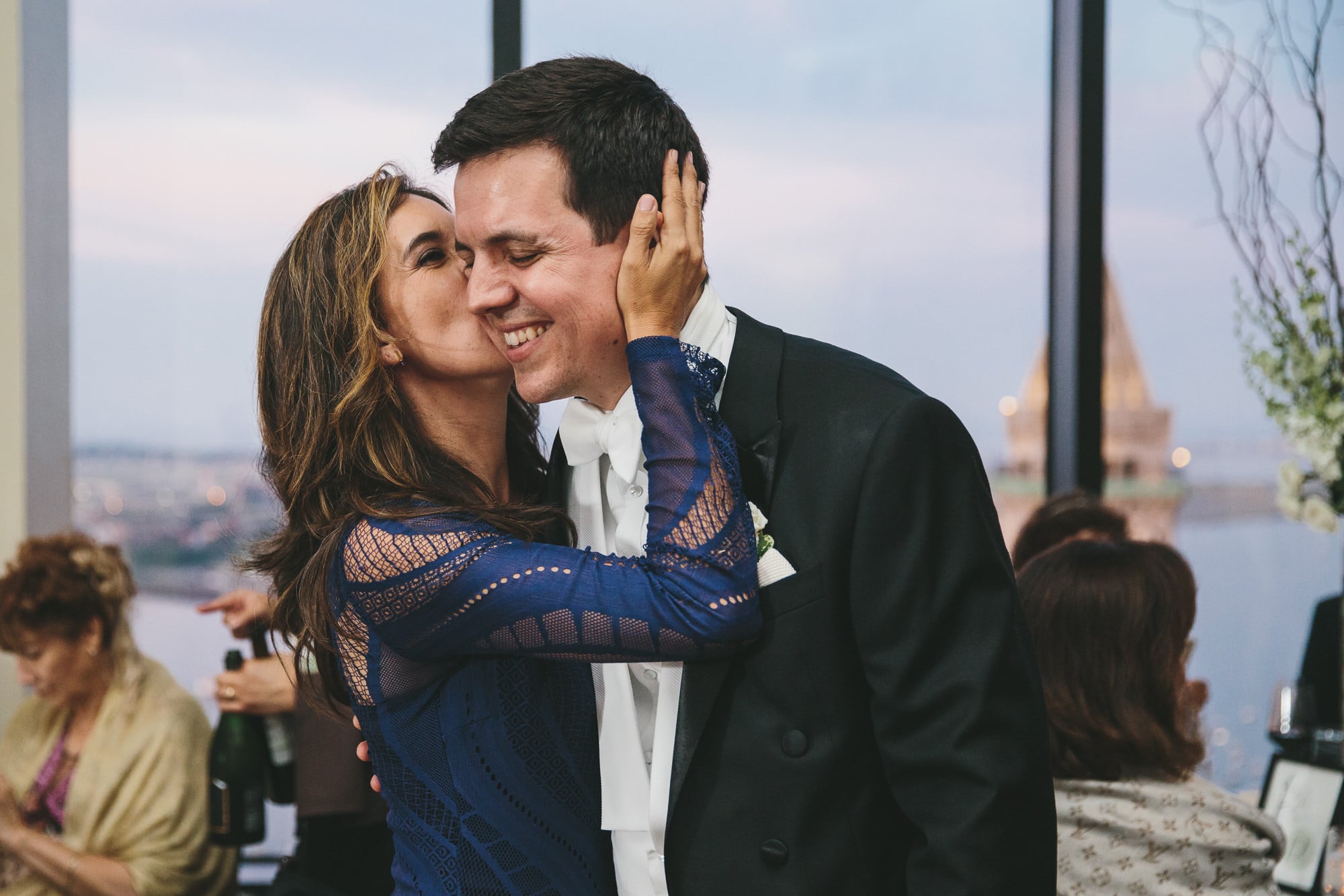 A documentary photograph of a guest hugging the groom during a state room wedding reception