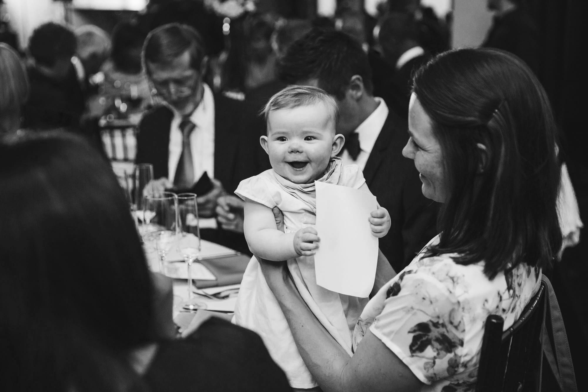 A documentary photograph of a baby laughing during a state room wedding reception