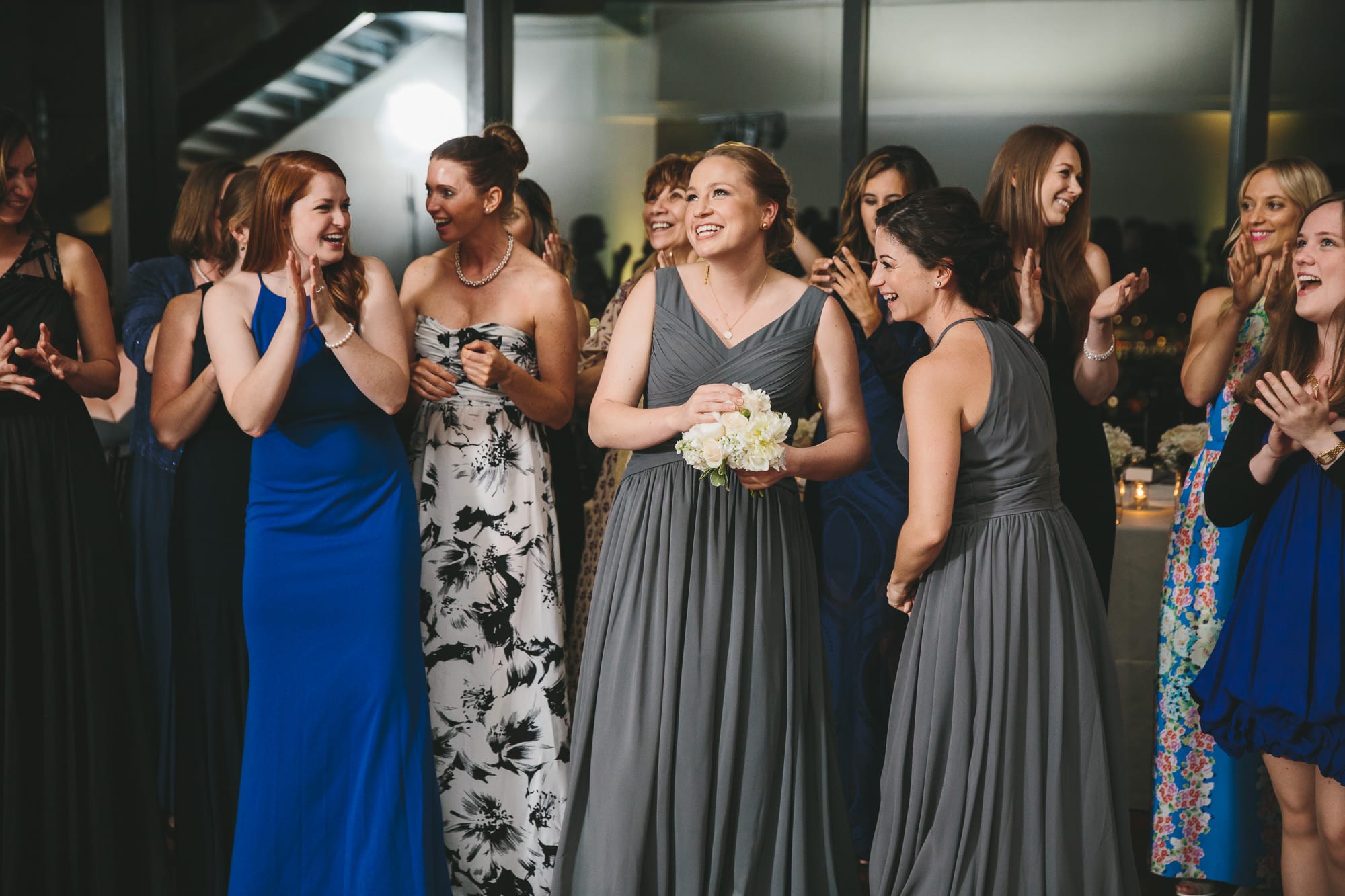 A documentary photograph of a bridesmaid catching the bouquet at a State Room Wedding