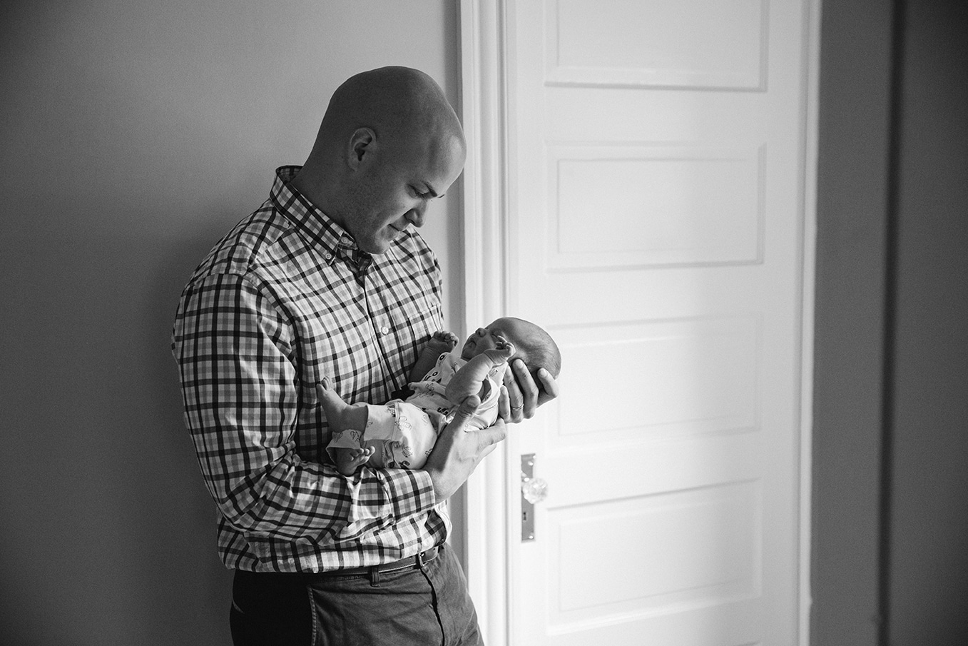 A lifestyle portrait of a father holding his newborn daughter during an in home session in Boston, Massachusetts