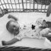 newborn stretches as her mother places her in to her bassinet during their lifestyle newborn session in Boston, Massachusetts