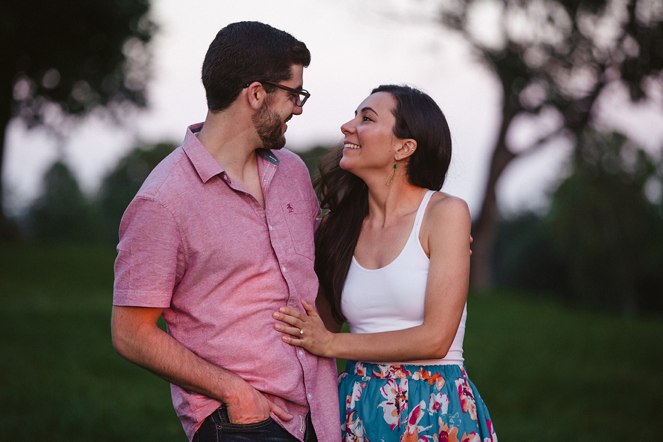 A couple smile at one another during their engagement session at the World's End in Hingham, Massachusetts