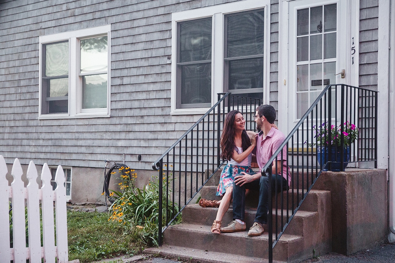 A documentary photograph of couple sitting together on their front steps after their World's End engagement session in Hingham, Massachusetts
