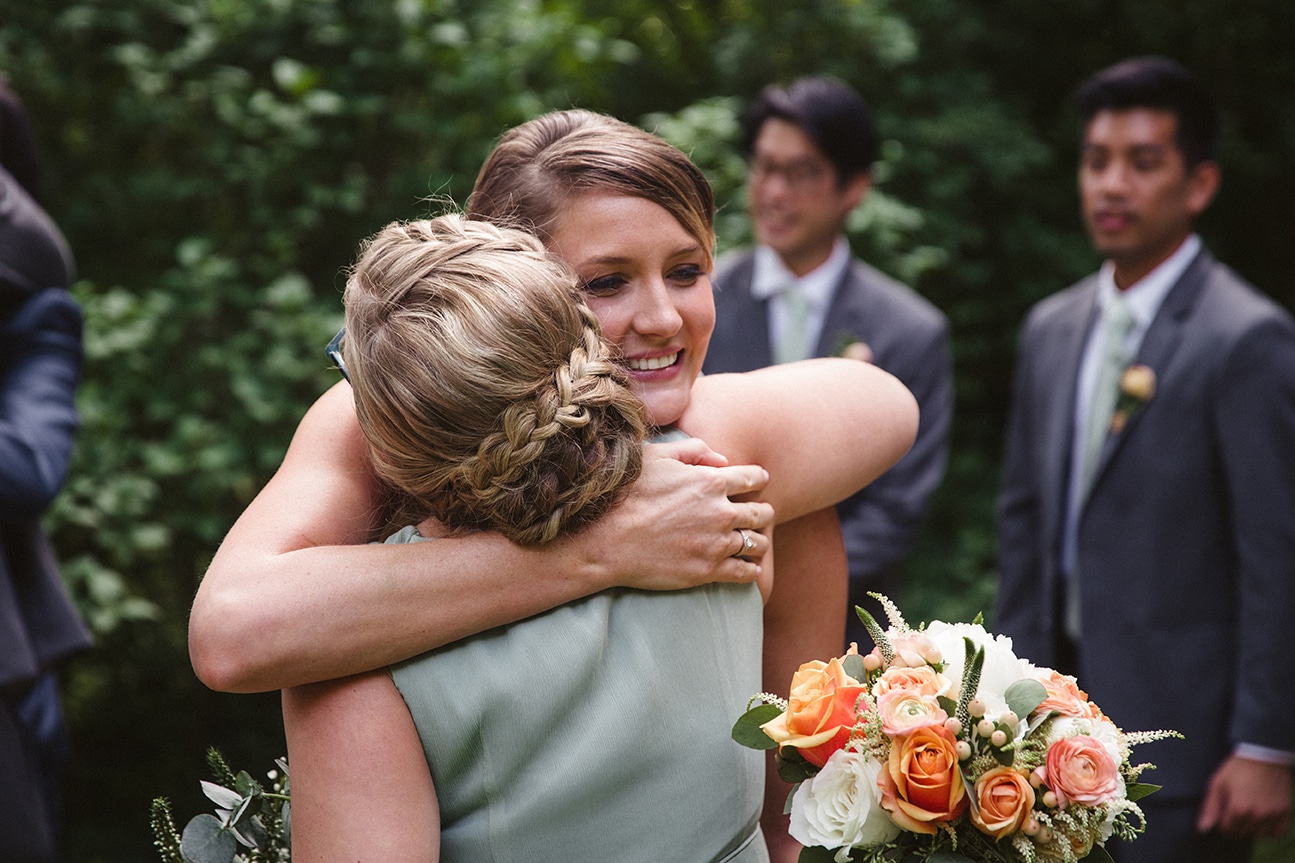 A documentary photograph of a bride hugging her sister after her outdoor plimoth plantation wedding ceremony in plymouth, massachusetts