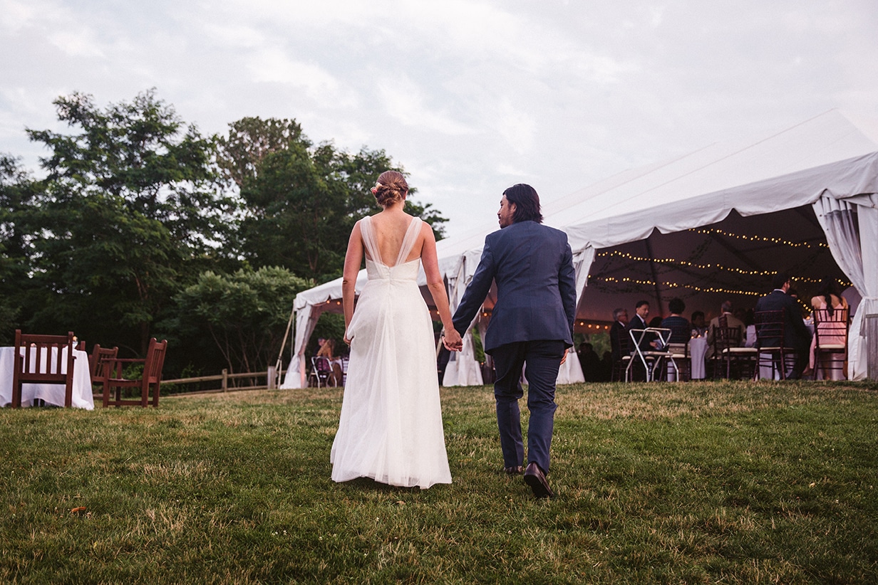 A documentary photograph of a bride and groom walking into their plimoth plantation reception in plymouth, massachusetts