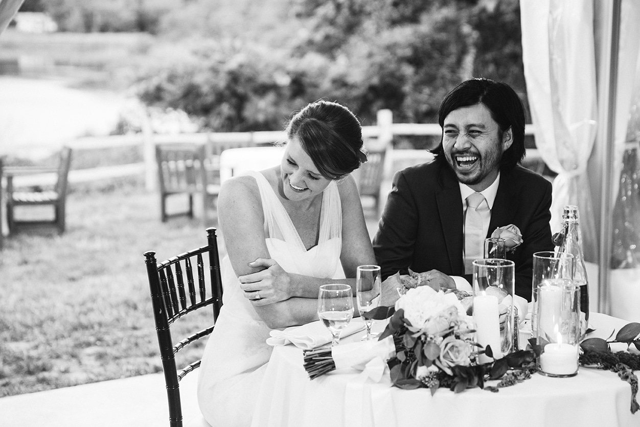 A documentary photograph of a bride and groom laughing during the toast at their plimoth plantation wedding in plymouth, massachusetts