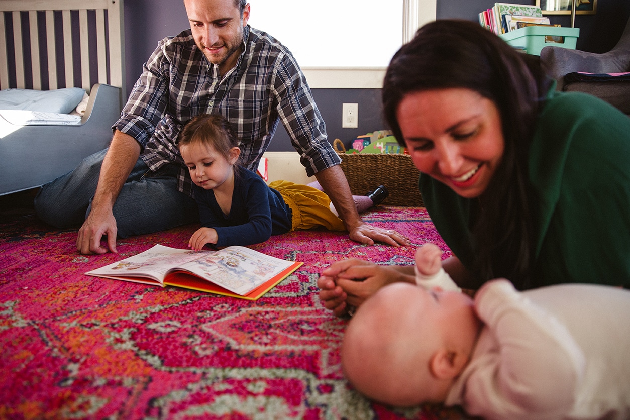 A documentary photograph of family hanging out and reading books during an in home family lifestyle session in Boston, Massachusetts