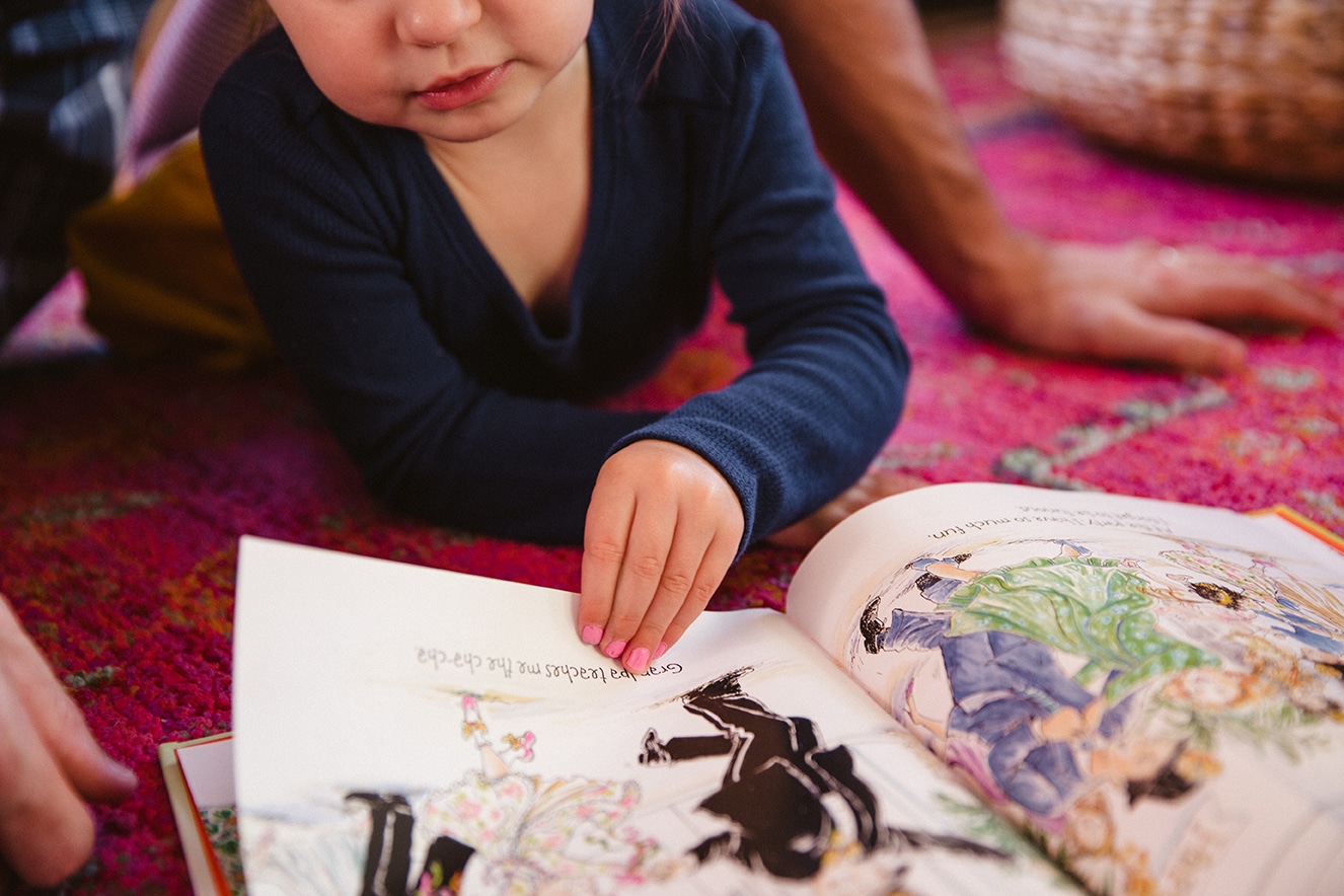 A documentary photograph of a little girl reading a book during an in home family lifestyle session in Boston, Massachusetts