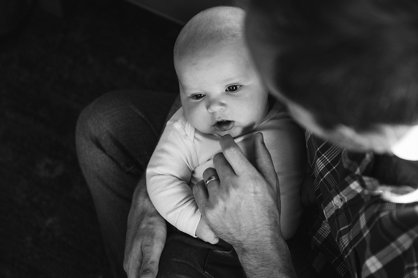 A documentary photograph of a dad holding his baby boy during an in home family lifestyle session in Boston, Massachusetts