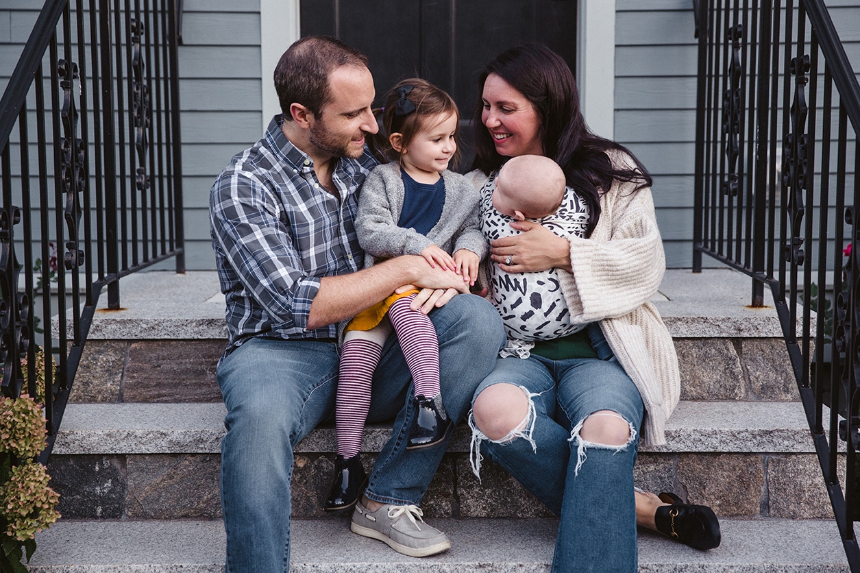 A documentary photograph of a family sitting on their front porch during an in home family lifestyle session in Boston, Massachusetts