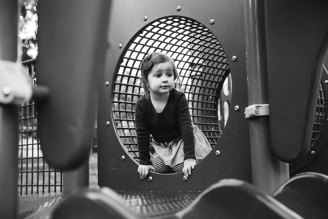 A documentary photograph of a little girl crawling through a tunnel during an in home family lifestyle session in Boston, Massachusetts