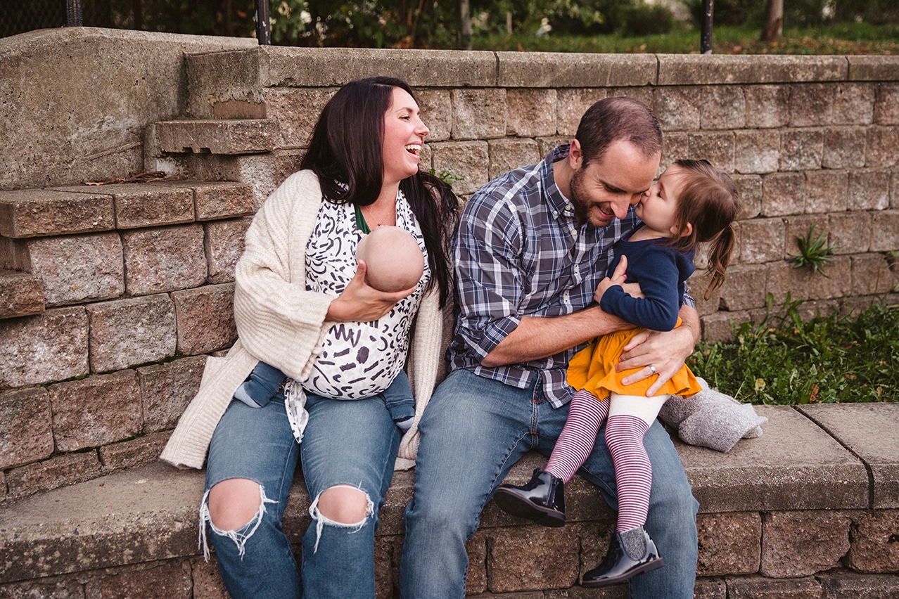A documentary photograph of a family laughing together at the playground during a family lifestyle session in Boston, Massachusetts