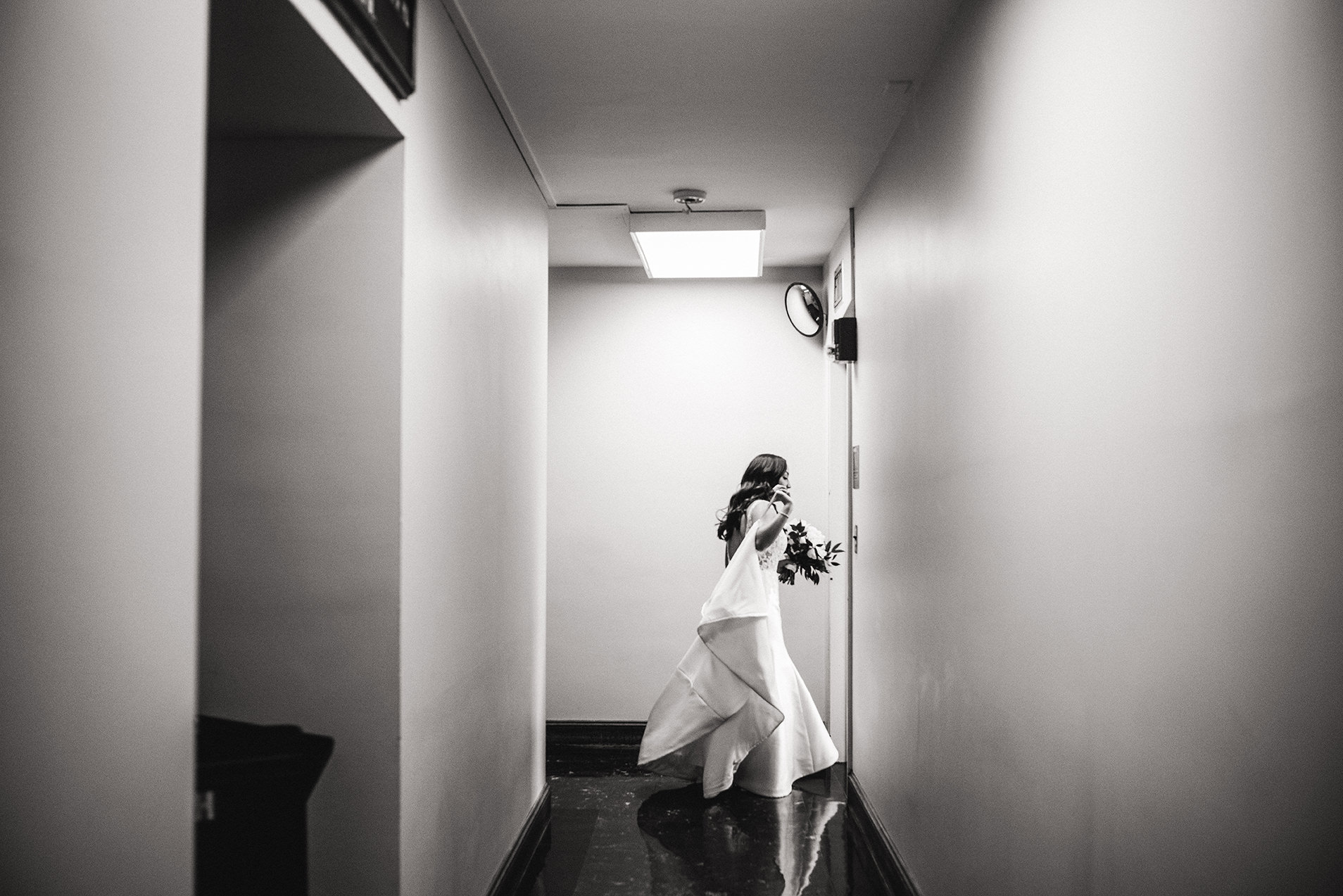 A documentary photograph of a bride walking in the hallway before her wedding ceremony in Boston