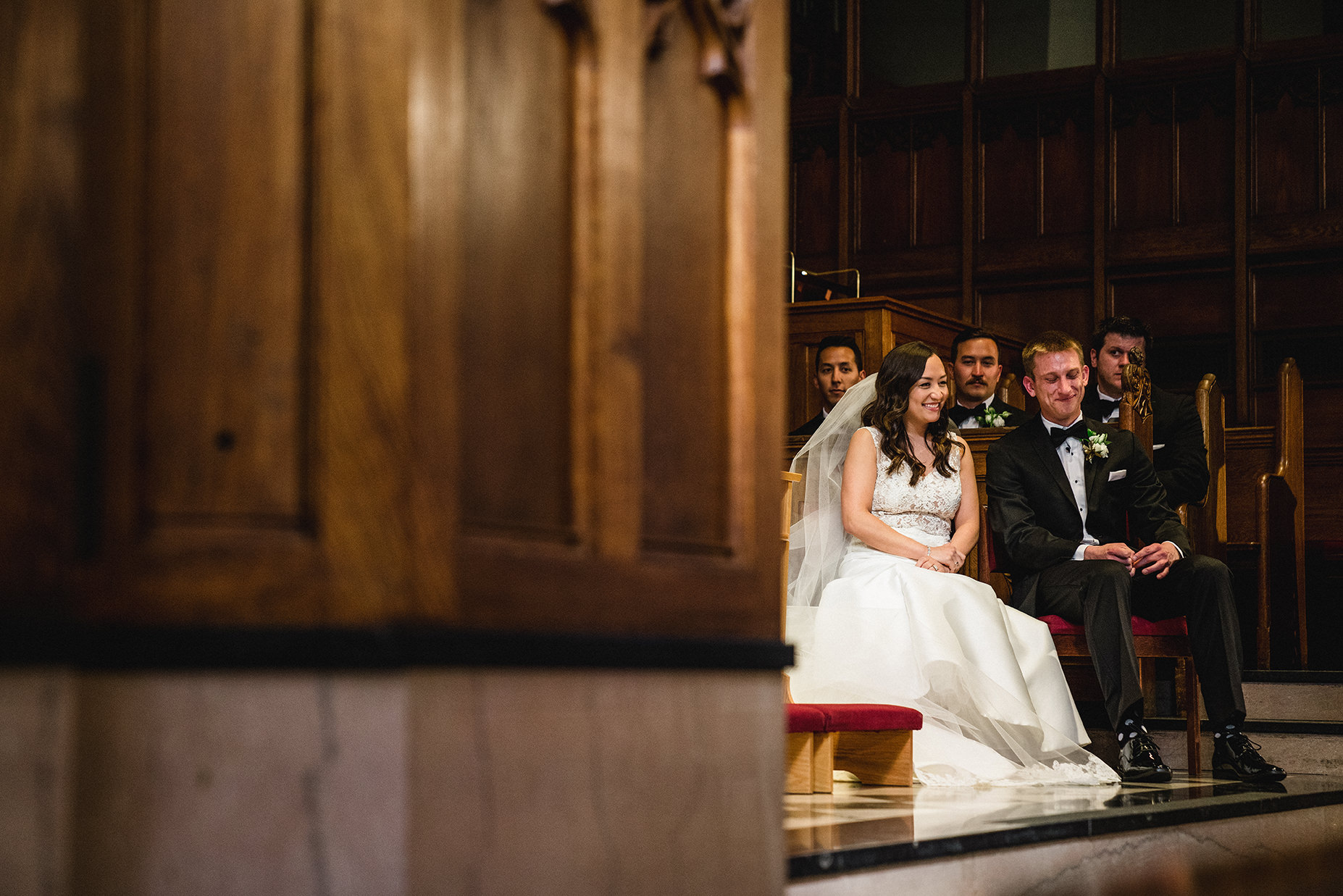 A documentary photograph of the bride and groom laughing during their wedding ceremony at Marsh Chapel in Boston